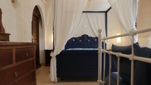 Ein Schlafzimmer mit einem Bett, einer Holzkommode und einem Himmelbett.