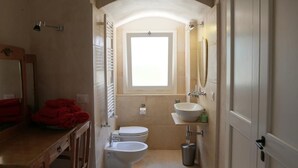 Ein Badezimmer mit Toilette, Bidet, Waschbecken und einem Fenster.