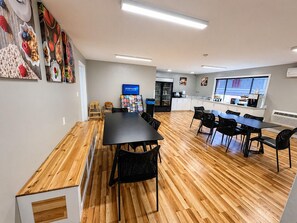 Cozinha moderna com uma ilha grande, área de jantar com mesa comprida e cadeiras, e uma geladeira.