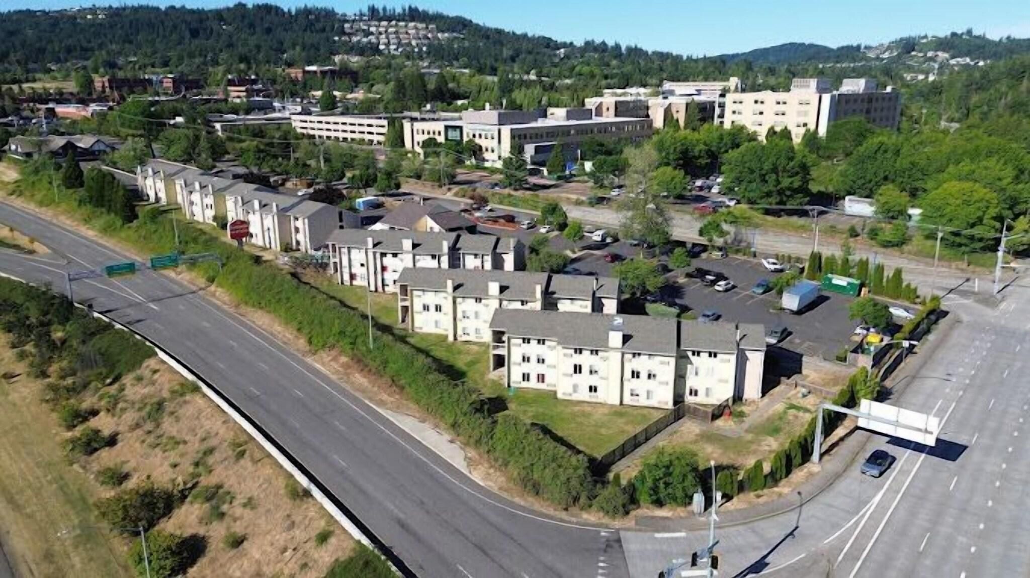 A residential area with detached houses, a main road, and a parking lot.