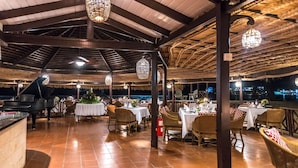 An outdoor dining area with tables and chairs, a piano, and hanging lights. - East Winds Inn (Gros Islet)