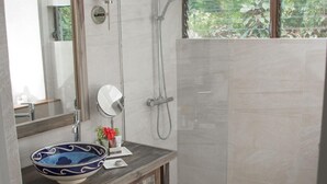 A modern bathroom with a large mirror, a round sink, and a shower area. - East Winds Inn (Gros Islet)