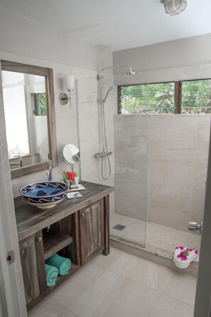A modern bathroom with a large mirror, a round sink, and a shower area. - East Winds Inn (Gros Islet)