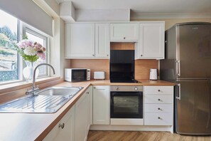 Eine moderne Küche mit weißen Schränken, einem Edelstahl-Kühlschrank, einem Einbauofen, einer Mikrowelle und einem Toaster.