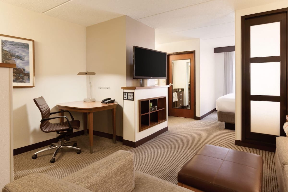Una habitación de hotel con escritorio, silla, televisión y cama.