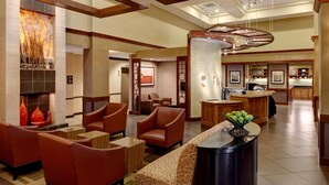 A hotel lobby with leather chairs, a fireplace, a reception desk, and a kitchen area. - Sonesta Select Tucson Airport (Tucson)