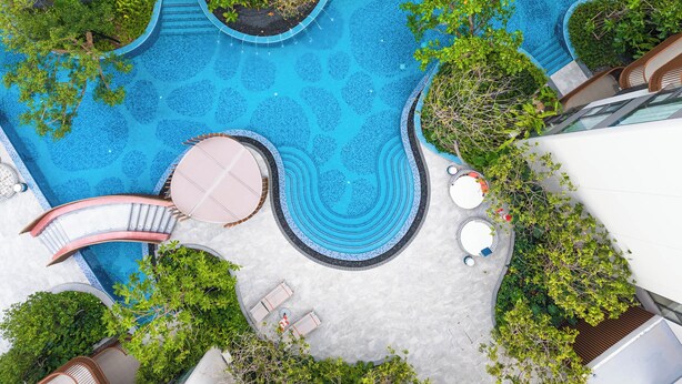 A rooftop pool with multiple levels, surrounded by greenery and lounge areas. - Luxury 2BR Pool Apartment in Bang Tao Phuket (Choeng Thale)