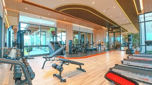 A modern gym with exercise equipment, large windows, and a wooden floor. - Luxury 2BR Pool Apartment in Bang Tao Phuket (Choeng Thale)