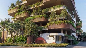 A multi-story building with balconies covered in greenery, a prominent 'CANVAS' sign, and a landscaped entrance area. - Luxury 2BR Pool Apartment in Bang Tao Phuket (Choeng Thale)
