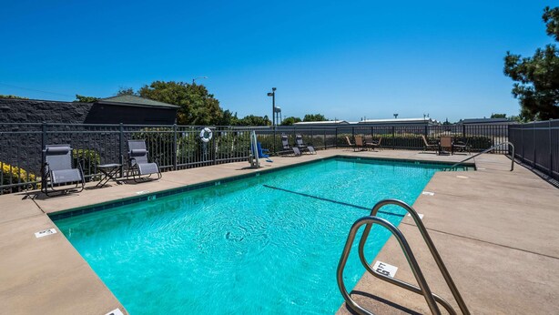 A clear blue swimming pool with lounge chairs and a lifeguard stand.