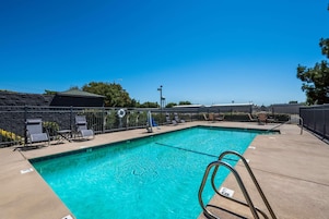 A clear blue swimming pool with lounge chairs and a lifeguard stand.