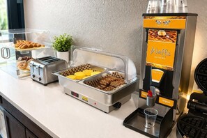 Ein reichhaltiges Buffet mit einem Waffeleisen, Toaster und verschiedenen Speisen.
