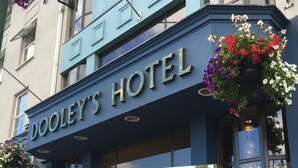 Hotel Dooley's, con un letrero llamativo, ventanas amplias y macetas colgantes de flores.