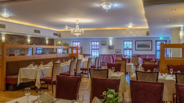 Un restaurante con varias mesas y sillas, una zona de bar y un candelabro.