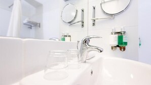Et moderne badeværelse med en hvid vask, kromarmaturer og to spejle på væggen.