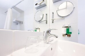 Un baño moderno con un lavamanos blanco, grifería cromada y dos espejos montados en la pared.