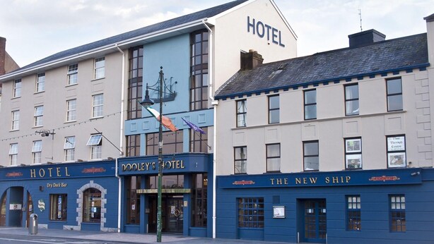 En række bygninger med skilte for 'HOTEL', 'DOOLEY'S HOTEL' og 'THE NEW SHIP'.