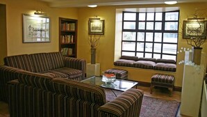 Sala de estar con sofás a rayas, una mesa de centro de vidrio, una estantería y un ventanal de múltiples paneles.