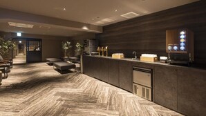 A reception area with a herringbone-patterned floor, a reception desk, seating area, and a coffee machine. - Taoya Nachikatsuura (Nachikatsuura)