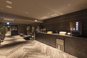A reception area with a herringbone-patterned floor, a reception desk, seating area, and a coffee machine. - Taoya Nachikatsuura (Nachikatsuura)