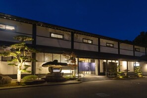 Un edificio japonés tradicional con un farol de piedra, un jardín cuidado y una entrada despejada.
