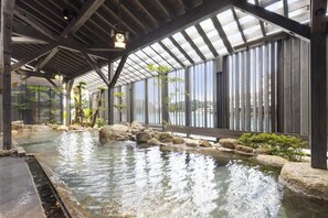 A covered outdoor pool with a wooden deck, large windows, and a view of the surrounding area. - Taoya Nachikatsuura (Nachikatsuura)