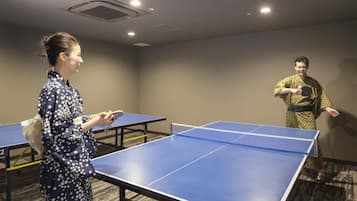 Ein Raum mit Tischtennisplatten, Teppichboden und einer Decke mit eingelassener Beleuchtung.