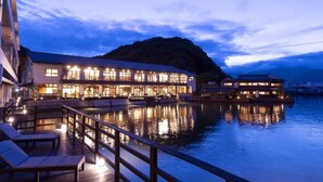 A waterfront hotel with a wooden deck, reflective water, and illuminated buildings. - Taoya Nachikatsuura (Nachikatsuura)