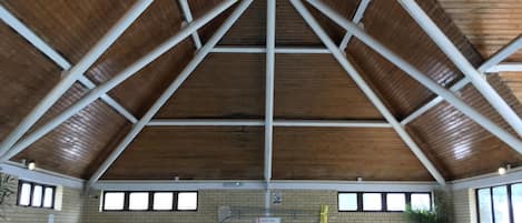 Una piscina interior con techo de madera y paredes de ladrillo.