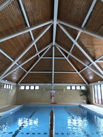 Una piscina interior con techo de madera y paredes de ladrillo.