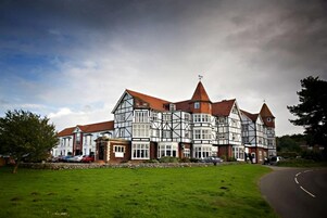 Un edificio de estilo Tudor tradicional con múltiples aleros y una torre central destacada.