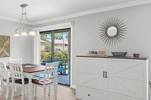 A dining area with a table and chairs, a cabinet with drawers, a decorative mirror, and a view of the outdoors. - 🐬Walk to Beach-5 Pools-Seascape Golf Villa 95E🦀 (Miramar Beach)
