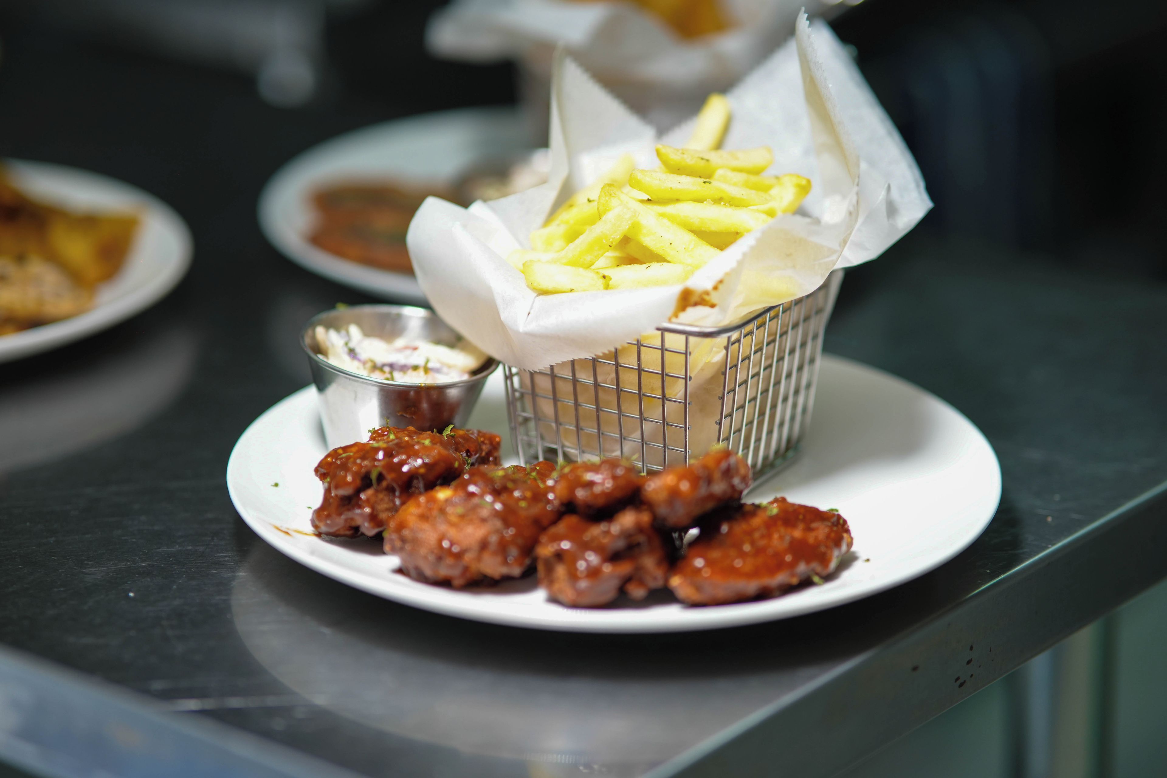 Un plato de comida con papas fritas y un recipiente pequeño de salsa.