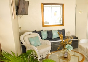 A living room with a white sofa, a glass coffee table, and a window with a view. - Vedanta Resort (Worthing)