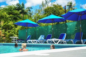 A swimming pool with blue umbrellas and lounge chairs. - Vedanta Resort (Worthing)