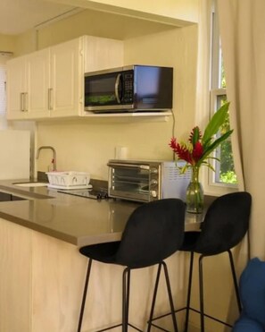 A modern kitchen with a microwave, toaster, and bar stools. - Vedanta Resort (Worthing)