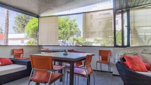 Un porche cubierto con mesa y sillas, un sofá y una silla de mimbre.
