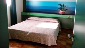 Ein Schlafzimmer mit einem Bett, einem Nachttisch, einer Topfpflanze und einem Fenster mit Vorhängen.