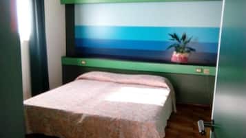 Una camera da letto con un letto, un comodino, una pianta in vaso e una finestra con tende.