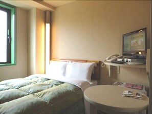 Una habitación de hotel con una cama, una mesa redonda con una revista, un televisor y un teléfono.