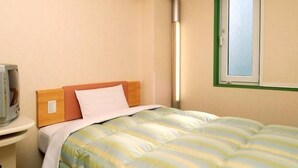 A single bed with a striped duvet, a bedside table with a lamp, and a window with a green frame. - R&B Hotel Sendai-hirosedoriekimae (Sendai)
