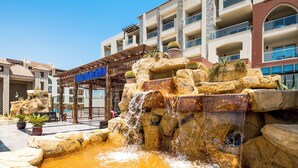 A hotel with a water feature, potted plants, and a clear blue sky. - Sunrise Alora (Hurghada)