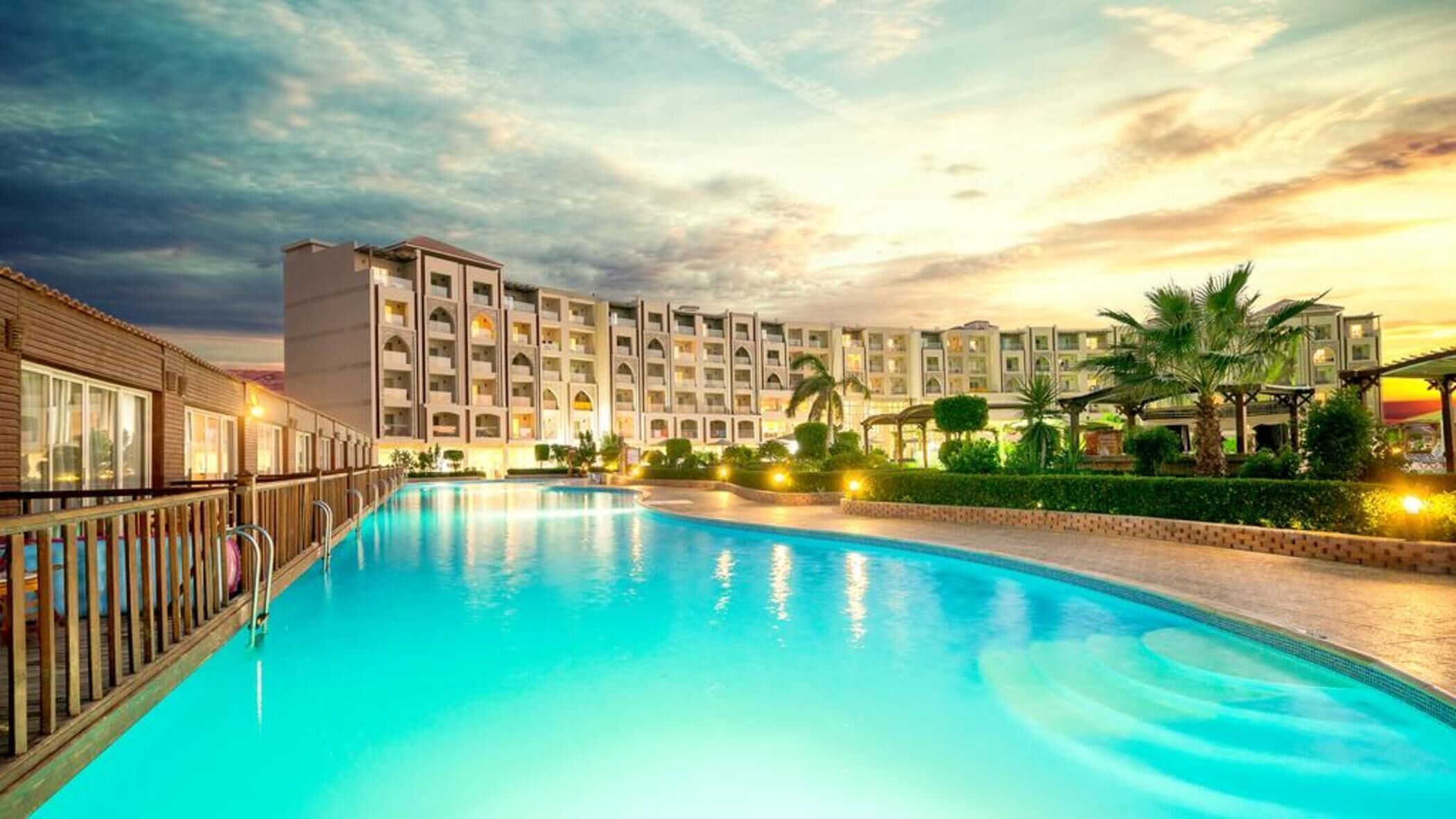 Un hôtel doté d’une piscine, de plusieurs balcons et offrant une vue sur le coucher de soleil.