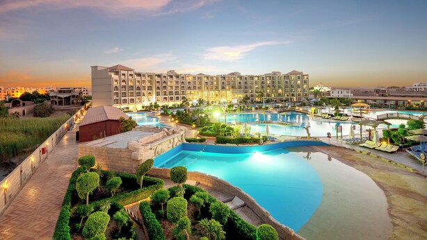 A resort with multiple swimming pools, a stone pathway, and a large building with multiple balconies. - Sunrise Alora (Hurghada)