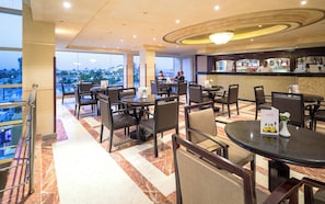 Un vestíbulo de hotel con varias zonas de estar, un bar y vistas a la ciudad.
