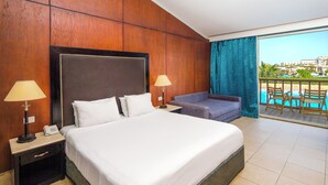A hotel room with a large bed, two bedside tables, a nightstand, a sofa, and a balcony with a pool view. - Sunrise Alora (Hurghada)
