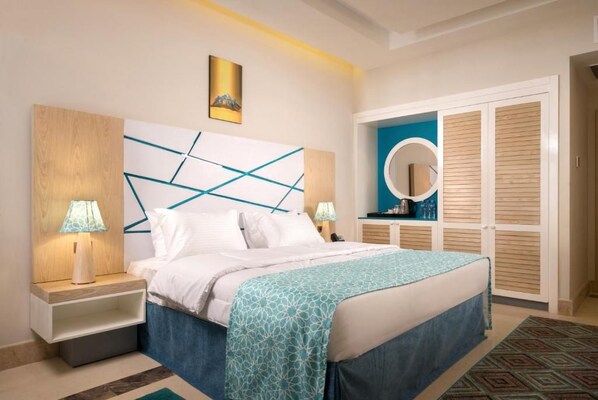 Ein Schlafzimmer mit Bett, Nachttischlampen, einem Kopfende mit geometrischen Mustern, einem Nachttisch, Wandkunst, einem runden Spiegel und einem Kleiderschrank mit Schiebetüren.