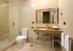 Ein Badezimmer mit Glasdusche, Toilette, Waschbecken mit Marmorplatte und Spiegel.