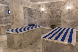 Un baño con suelo de mármol y dos lavamanos, cada uno cubierto con un paño azul y blanco a rayas.