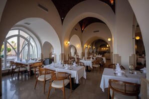 A restaurant with multiple tables and chairs, arched ceilings, and large windows. - Shams Alam Beach Resort (Marsa Alam)